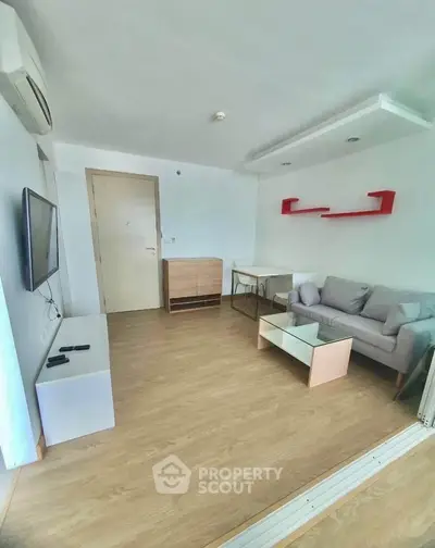 Modern living room with sleek furniture and wooden flooring, featuring a wall-mounted TV and stylish shelving.