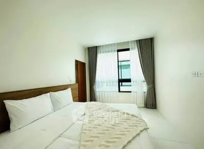 Spacious and bright bedroom with modern decor and large window for natural light.