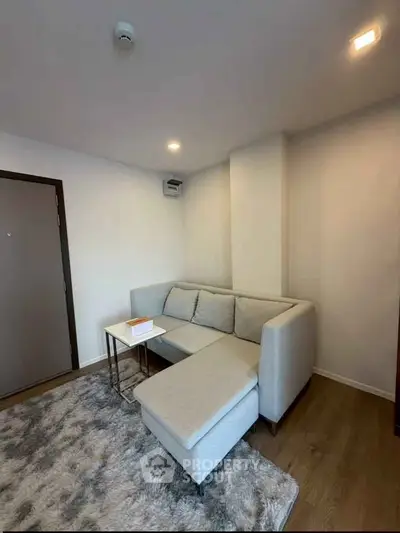 Cozy living room with modern L-shaped sofa and plush rug, perfect for relaxation.