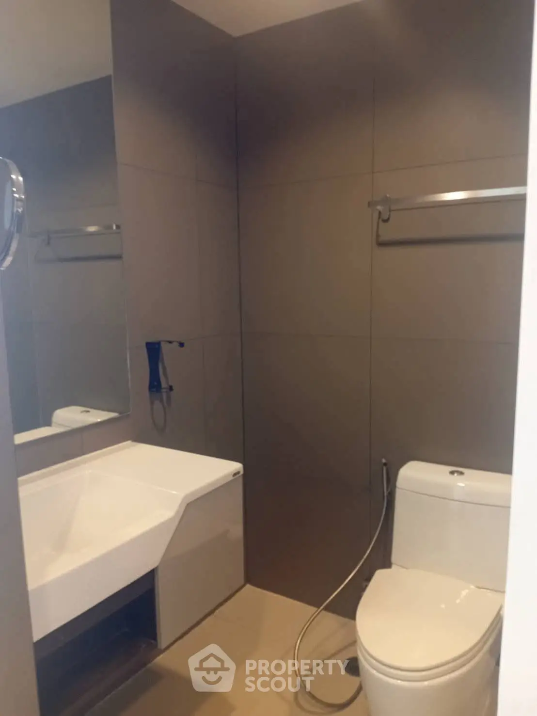 Modern bathroom with sleek fixtures and neutral tones, featuring a toilet and a stylish sink.