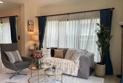 Elegant living room with cozy sofa, stylish armchair, and large window with curtains, perfect for relaxation.