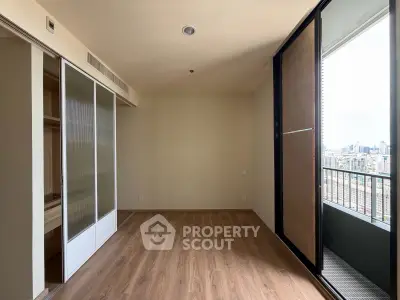 Spacious empty room with wooden flooring and city view balcony, perfect for customization.