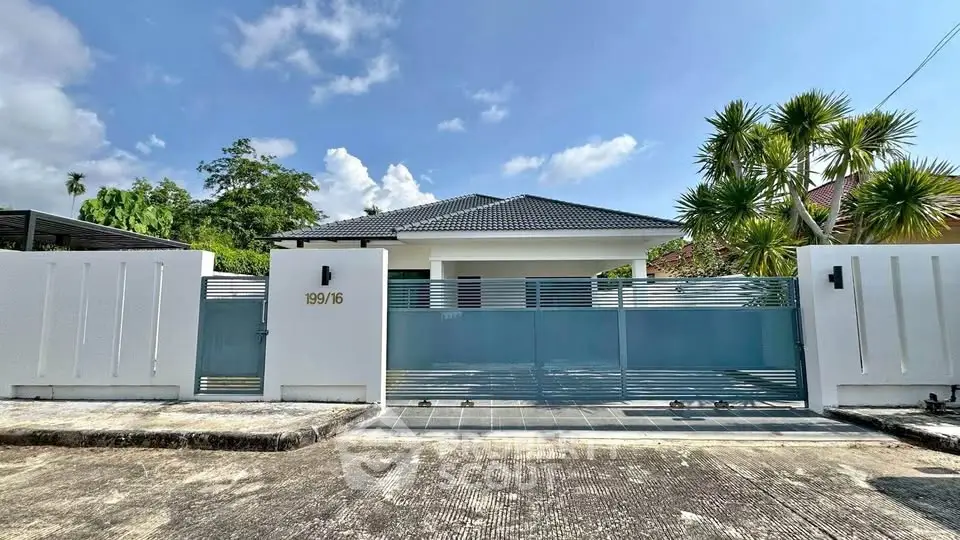 Modern single-story house with sleek gate and tropical landscaping