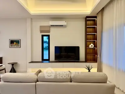 Modern living room with stylish decor and natural light, featuring a cozy sofa and sleek entertainment center.