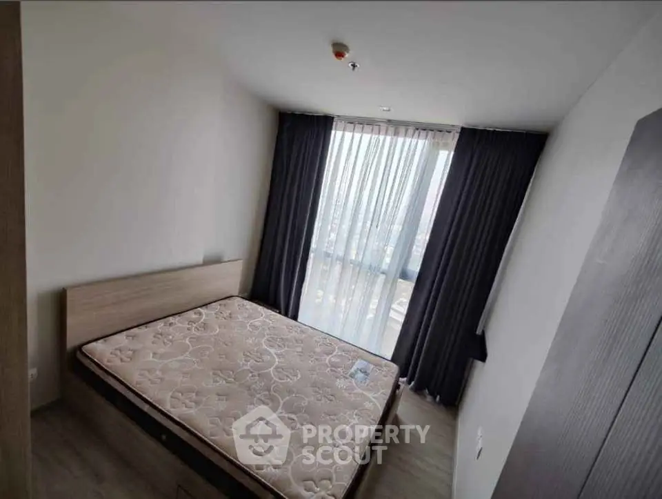 Spacious bedroom with large window and modern design in a high-rise apartment.