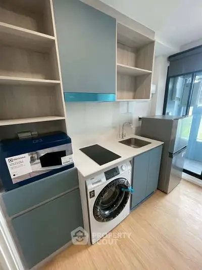 Modern kitchen with sleek cabinets, washing machine, and compact fridge in a stylish apartment.
