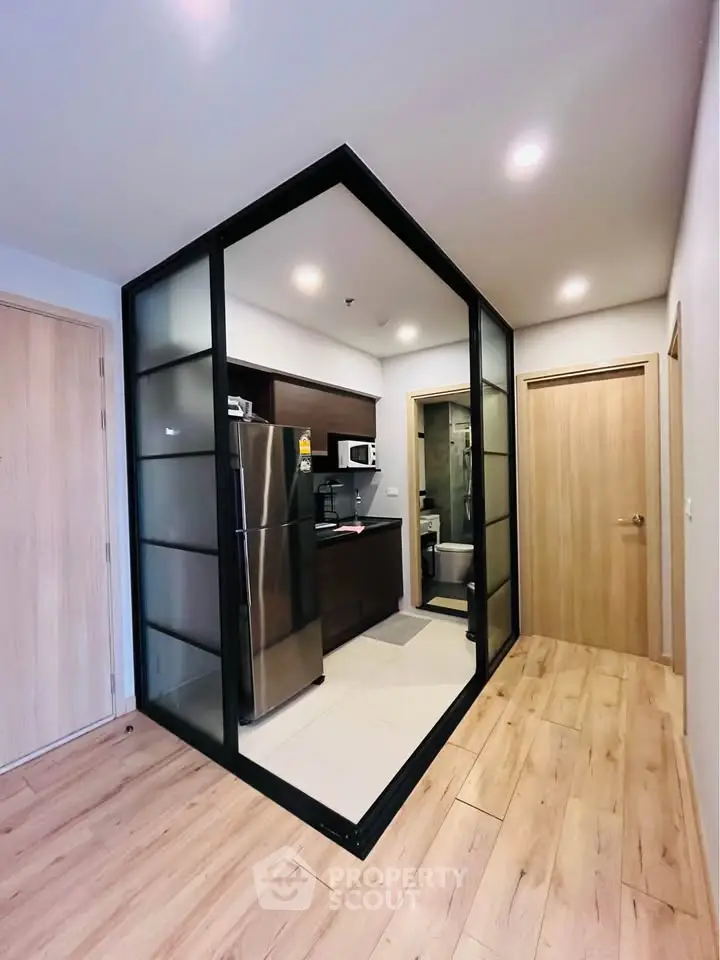 Modern kitchen with glass partition and sleek appliances in a stylish apartment.