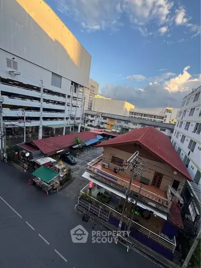 Urban street view with residential and commercial buildings under a clear sky.