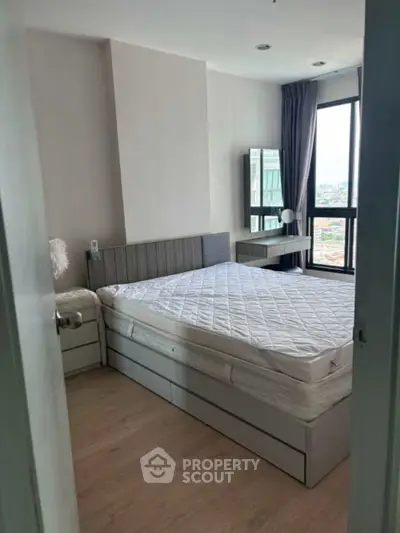 Modern bedroom with large window and city view, featuring sleek furniture and neutral tones.