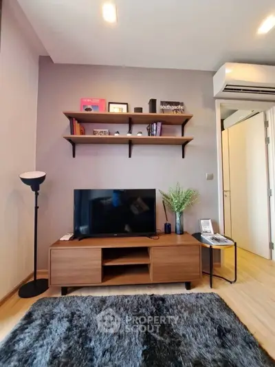 Modern living room with stylish decor, wall-mounted shelves, and cozy rug, perfect for relaxation and entertainment.