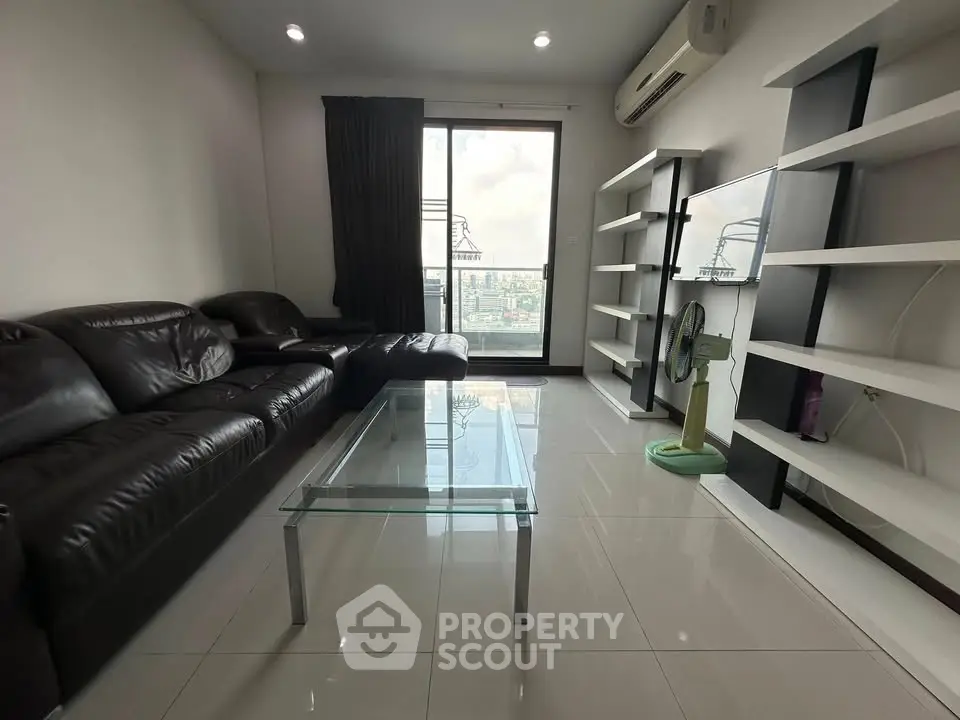 Modern living room with leather sofa, glass coffee table, and city view balcony.