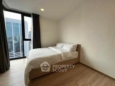 Modern bedroom with large window and wooden flooring in urban apartment