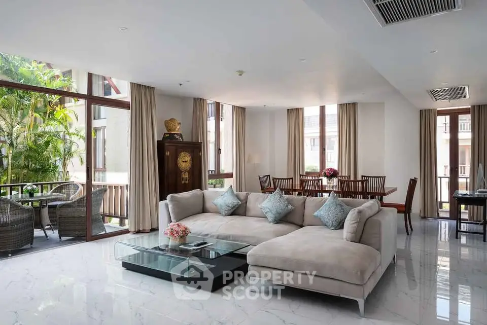 Luxurious living room with elegant decor and large windows overlooking lush greenery.