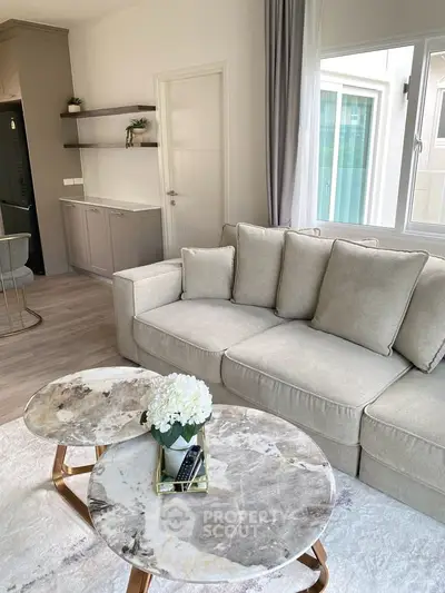 Elegant living room with plush beige sofa and stylish marble coffee tables, perfect for modern comfort.