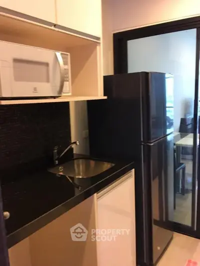 Modern compact kitchen with microwave and fridge in sleek apartment