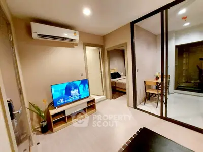 Modern living room with TV and air conditioning, leading to a cozy bedroom and dining area.