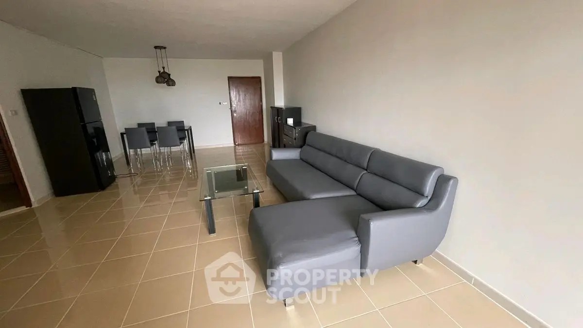 Spacious modern living room with sleek gray sofa and dining area