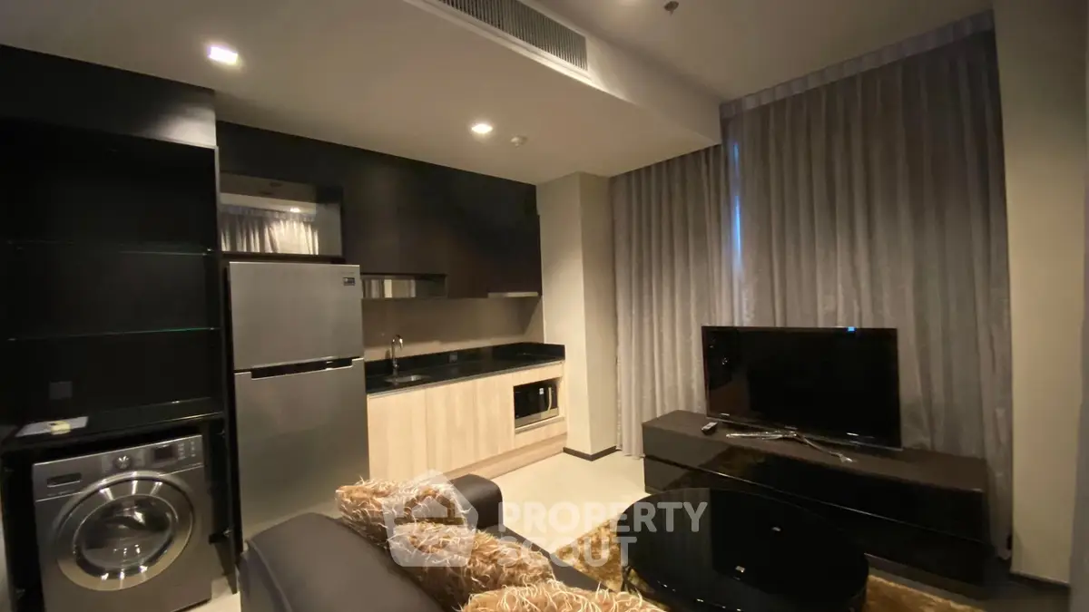 Modern apartment living room with sleek kitchen and cozy seating area.