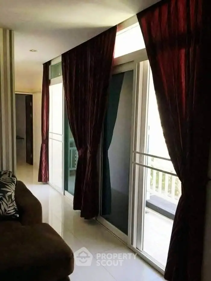 Spacious living room with large sliding glass doors and elegant curtains leading to a balcony.