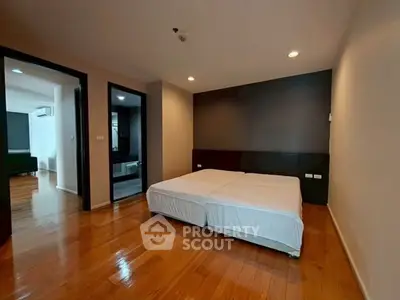 Spacious bedroom with wooden flooring and twin beds in modern apartment