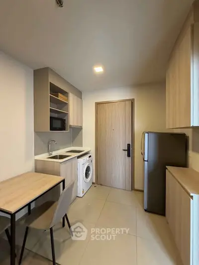 Modern compact kitchen with washing machine and fridge in a cozy apartment.