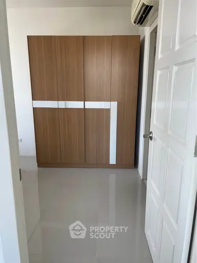 Modern bedroom with sleek wooden wardrobe and glossy tiled floor