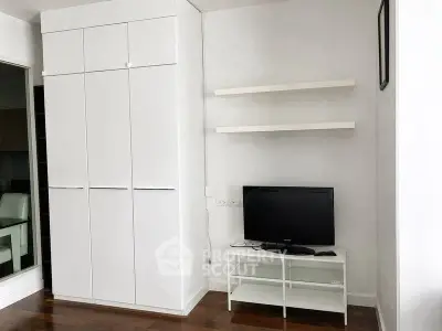 Modern living room with sleek white cabinets and TV stand, featuring minimalist design and wooden flooring.