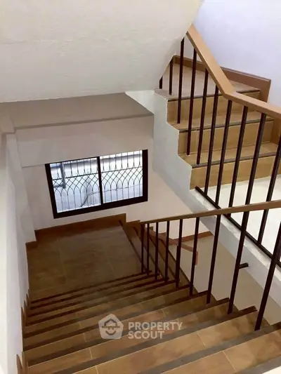 Elegant staircase with wooden steps and metal railing in modern home interior.