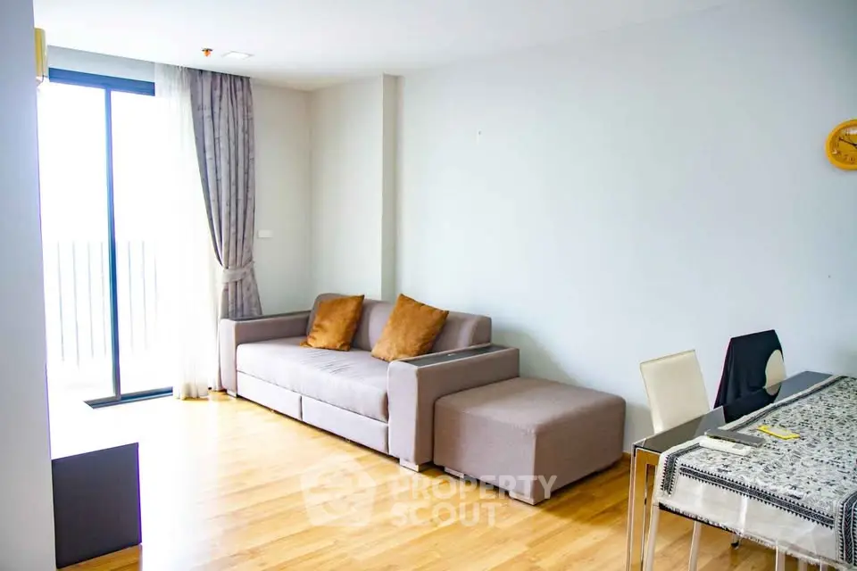 Modern living room with stylish sofa and dining area, featuring natural light and wooden flooring.