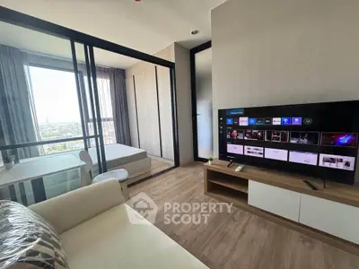 Modern living room with TV and view into a stylish bedroom through glass partition.