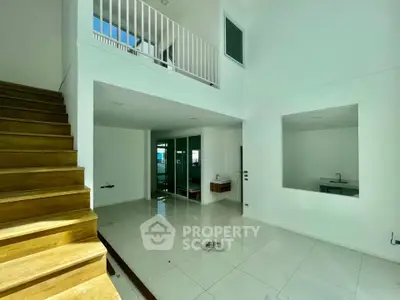 Spacious modern interior with high ceilings and wooden staircase, perfect for contemporary living.
