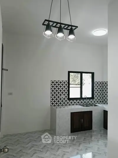 Modern kitchen with stylish lighting and geometric backsplash in a sleek, minimalist design.