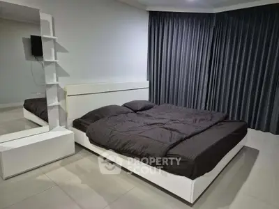 Modern bedroom with sleek design and large mirror, featuring a cozy bed and stylish curtains.