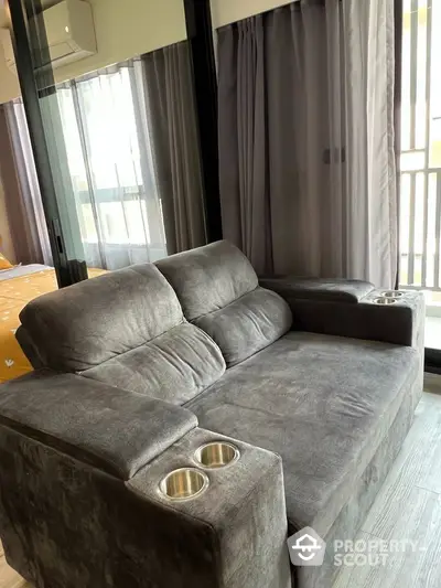 Modern living room with plush gray sofa and large windows for natural light.