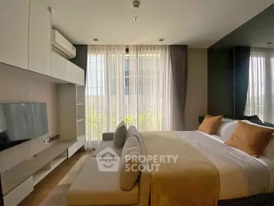 Modern bedroom with large windows, cozy bed, and sleek entertainment unit in a stylish apartment.