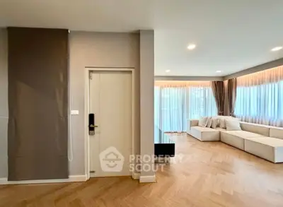 Spacious modern living room with elegant herringbone flooring and large windows for natural light.