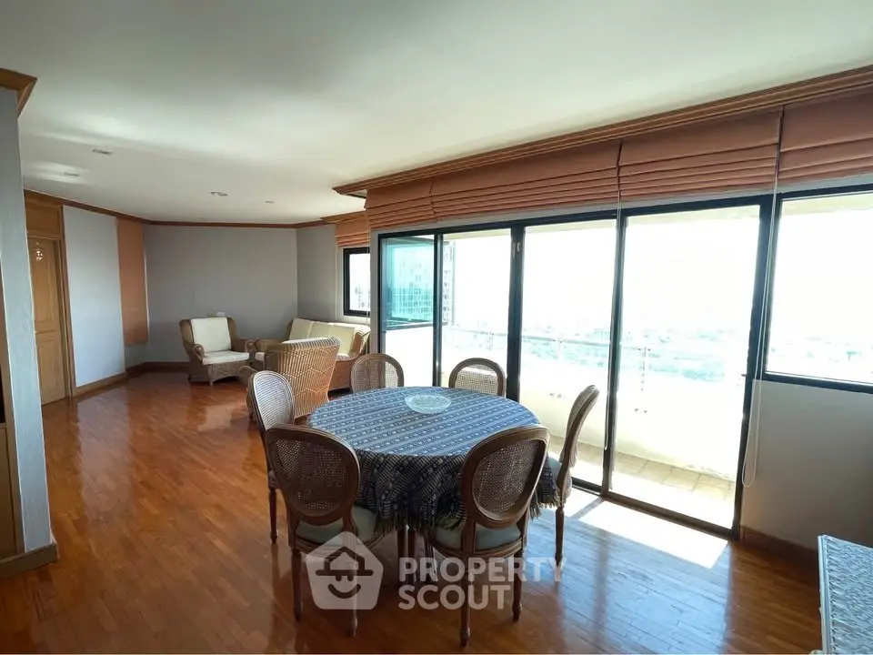 Spacious living room with elegant dining area and large windows offering stunning city views.