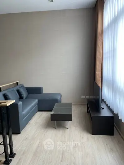 Modern living room with sleek furniture and large window, perfect for cozy relaxation.