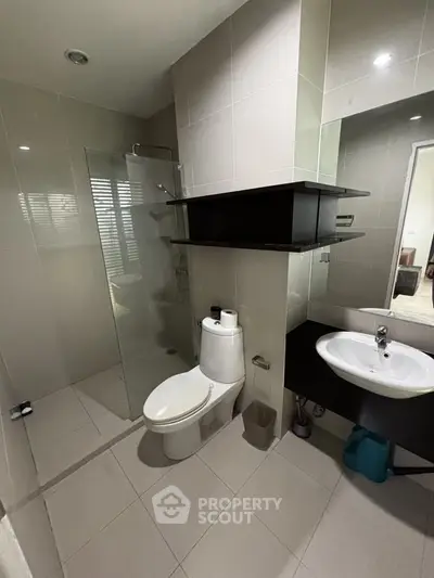 Modern bathroom with sleek design, featuring a glass shower enclosure and contemporary fixtures.
