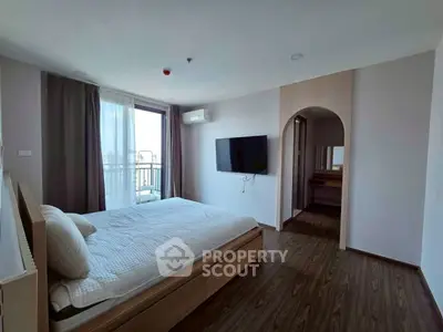 Spacious modern bedroom with balcony access and wall-mounted TV in a stylish apartment.