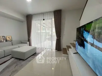 Modern living room with sleek design, large TV, and floor-to-ceiling windows for natural light.
