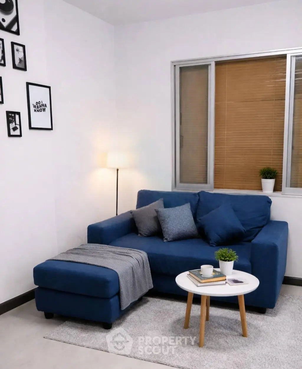 Cozy living room with blue sofa, modern decor, and natural light through window.