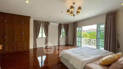 Spacious bedroom with elegant wooden flooring and large windows for natural light.