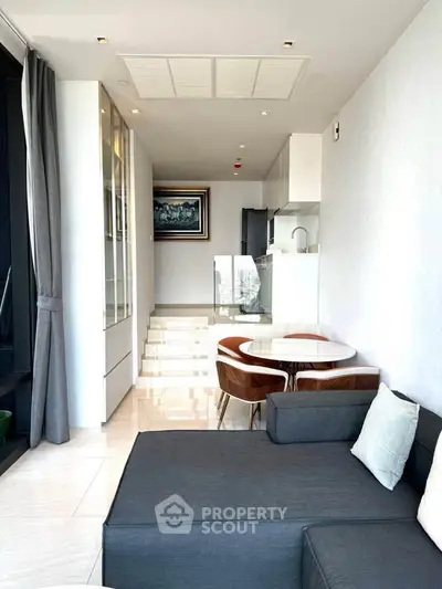 Modern living room with sleek furniture and open kitchen layout, featuring a stylish dining area.