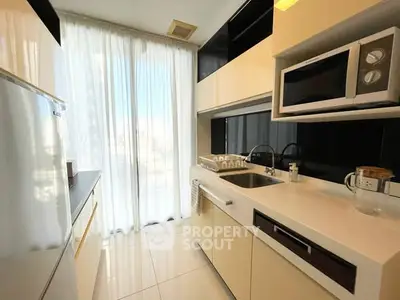 Modern kitchen with sleek cabinetry, microwave, and large window for natural light.