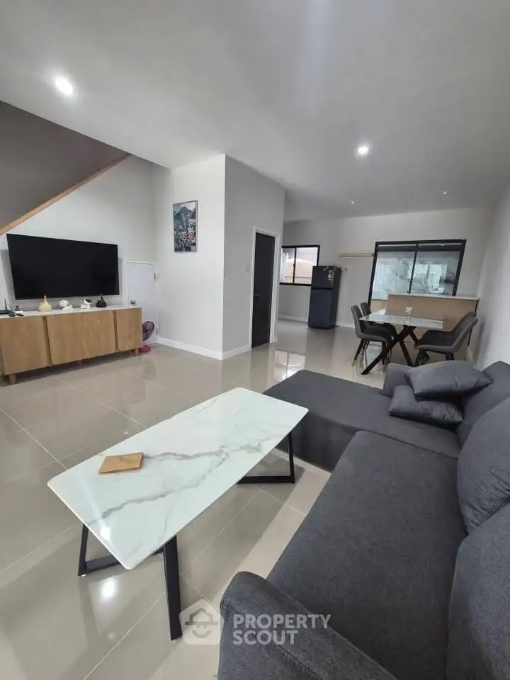 Spacious modern living room with sleek furniture and open dining area.