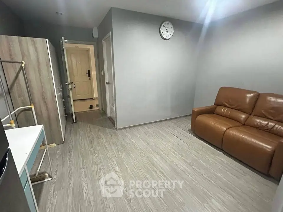 Modern living room with sleek flooring and leather sofa, featuring a minimalist design and ample natural light.