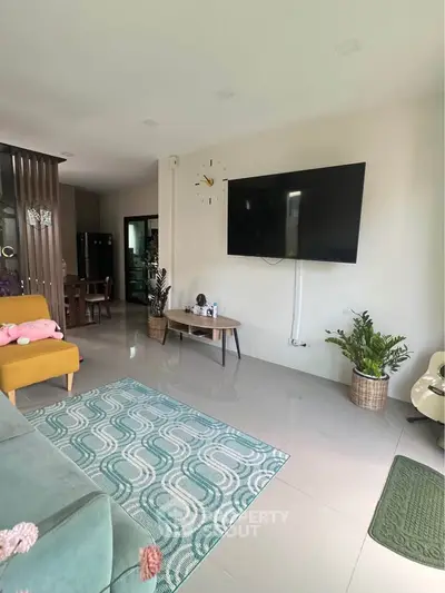 Modern living room with large TV, stylish furniture, and decorative plants in a cozy home setting.