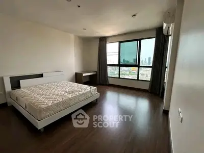 Spacious bedroom with city view and modern furnishings in high-rise apartment.