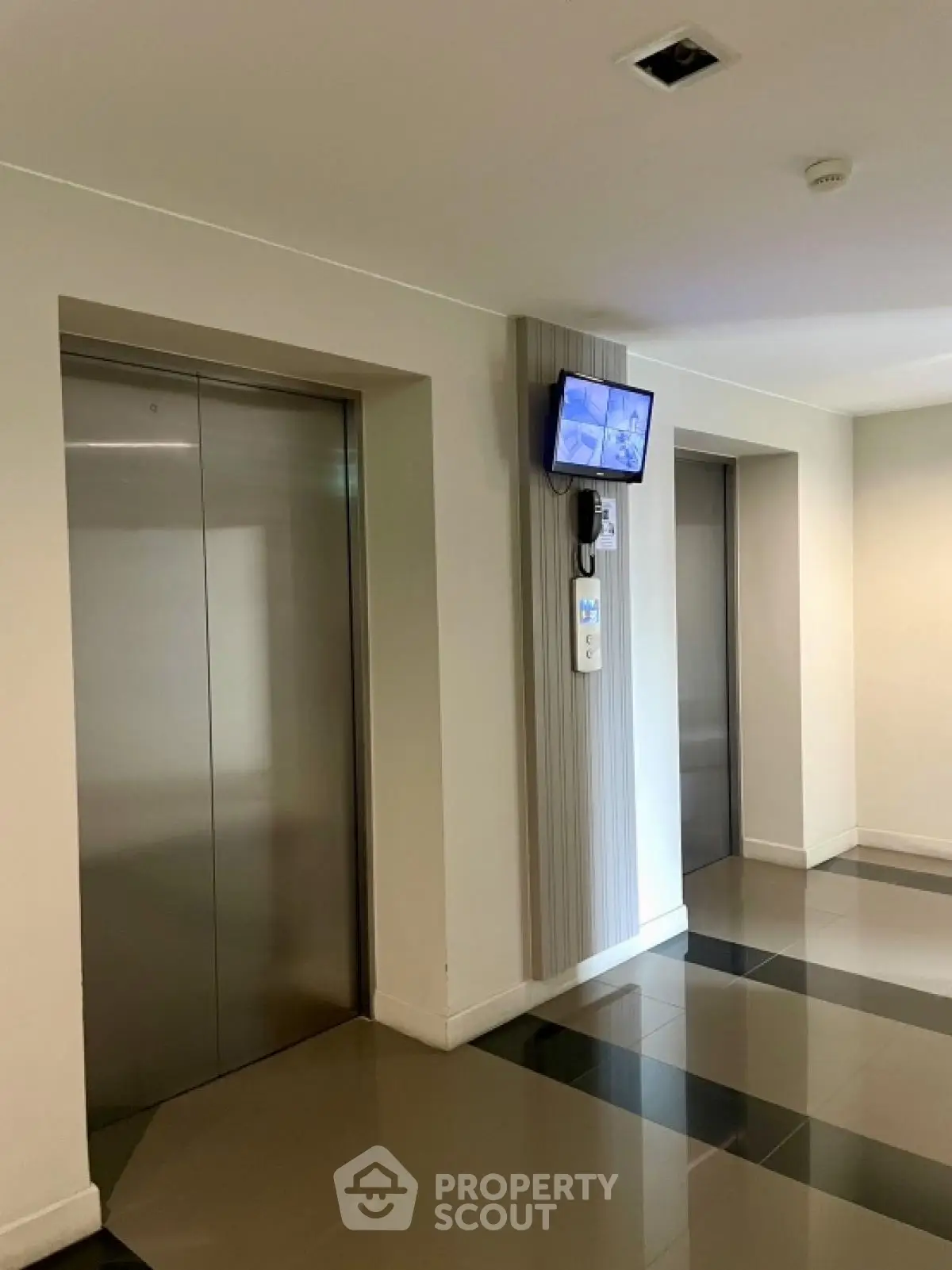 Modern building elevator lobby with sleek design and security monitor